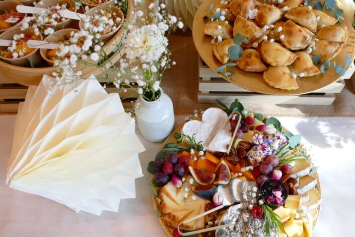 Jolie table thème mariage avec petites brochettes, salades, planche de fromages, feuilletés, sablés décorés wedding day, financiers, décoration or, blanc et petits bouquets de gypsophille