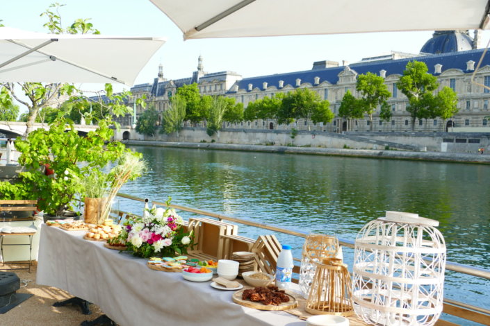 Petit déjeuner sur une péniche face au Louvre par studio Candy : beignets, financiers, sablés décorés, granola, fruits frais et décoration estivale