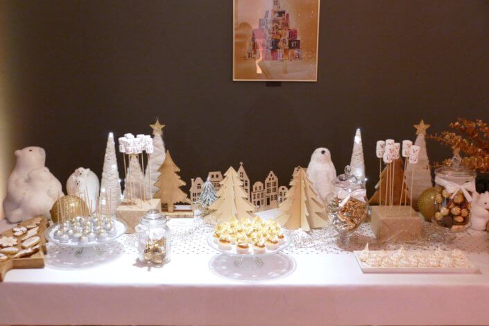 Soirée de Noël Adopt par Studio Candy avec une grande table de Noël décorée en or et blanc. Cakepops au chocolat, cupcakes, sapins meringue, sablés de Noël et corbeille de fruits et cocktail salé avec verrines, grazing platters, cônes garnis