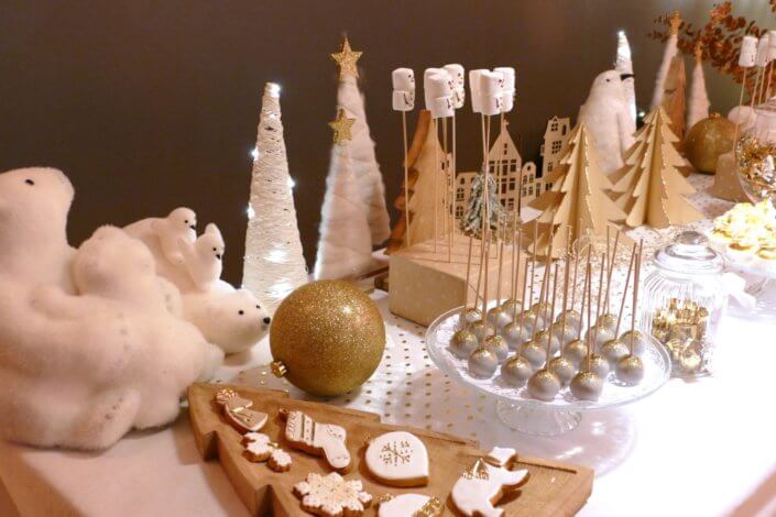 Soirée de Noël Adopt par Studio Candy avec une grande table de Noël décorée en or et blanc. Cakepops au chocolat, cupcakes, sapins meringue, sablés de Noël et corbeille de fruits et cocktail salé avec verrines, grazing platters, cônes garnis