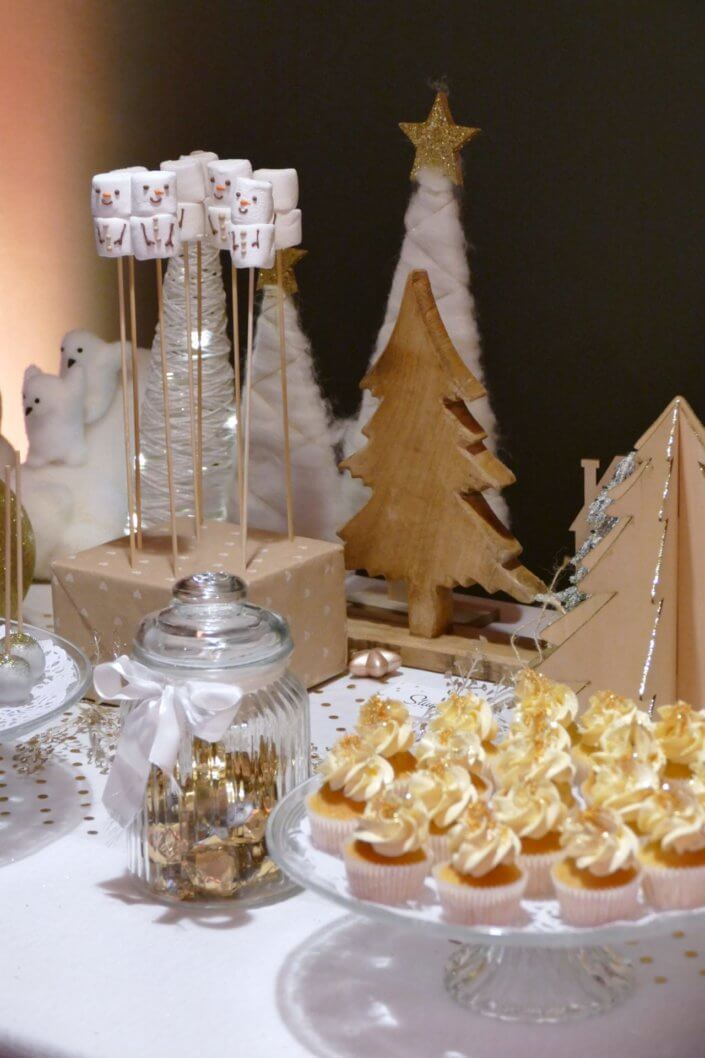 Soirée de Noël Adopt par Studio Candy avec une grande table de Noël décorée en or et blanc. Cakepops au chocolat, cupcakes, sapins meringue, sablés de Noël et corbeille de fruits et cocktail salé avec verrines, grazing platters, cônes garnis