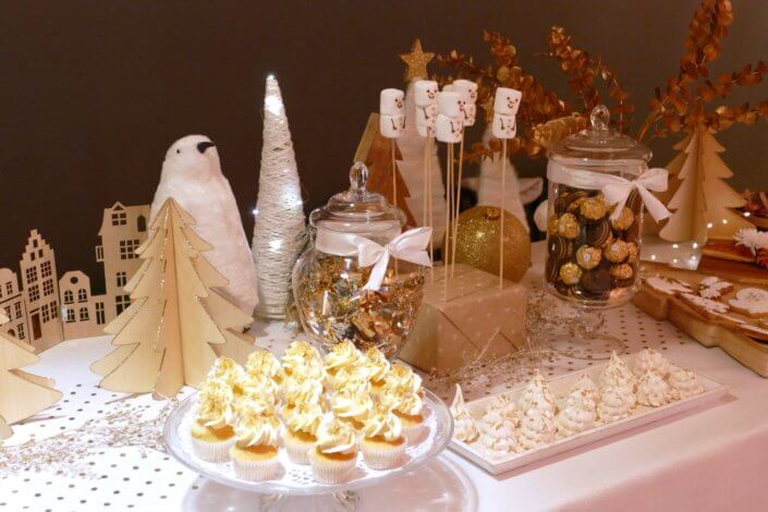 Soirée de Noël Adopt par Studio Candy avec une grande table de Noël décorée en or et blanc. Cakepops au chocolat, cupcakes, sapins meringue, sablés de Noël et corbeille de fruits et cocktail salé avec verrines, grazing platters, cônes garnis