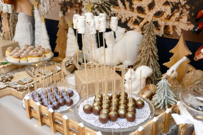 Noel nature par studio candy avec une décoration en beige et doré, des cakepops au chocolat, des mini cupcakes, des sablés décorés de Noël, un candy bar de chocolats et des ballons mignons pour les enfants