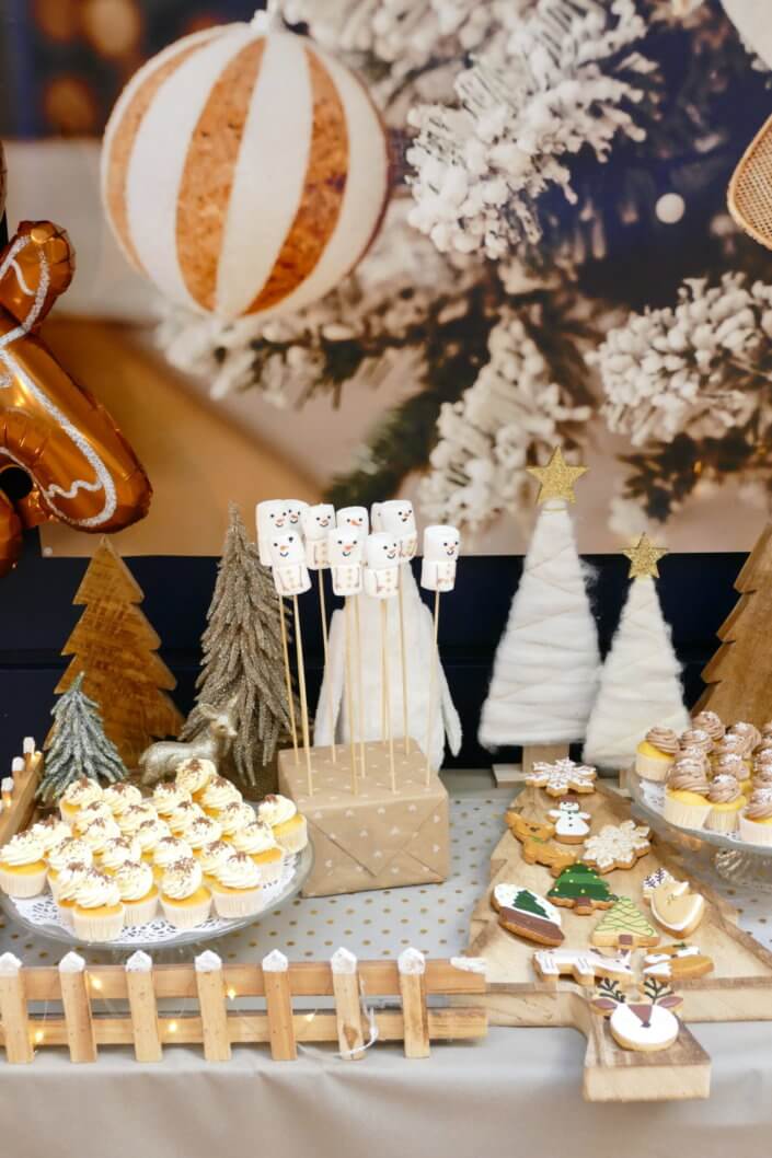 Noel nature par studio candy avec une décoration en beige et doré, des cakepops au chocolat, des mini cupcakes, des sablés décorés de Noël, un candy bar de chocolats et des ballons mignons pour les enfants