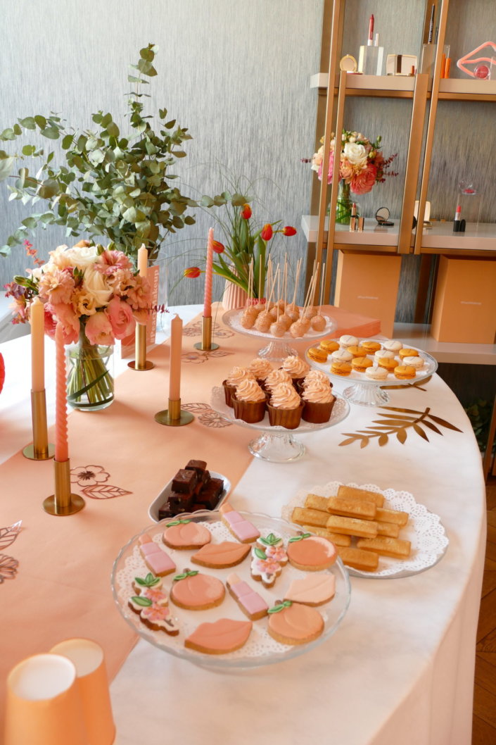 Evénement pêche Estée Lauder par Studio Candy avec table sur mesure décorée avec cakepops et cupcakes pêches, sablés décorés personnalisés, planches cocktail estivales et fontaines à boissons