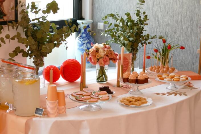 Evénement pêche Estée Lauder par Studio Candy avec table sur mesure décorée avec cakepops et cupcakes pêches, sablés décorés personnalisés, planches cocktail estivales et fontaines à boissons