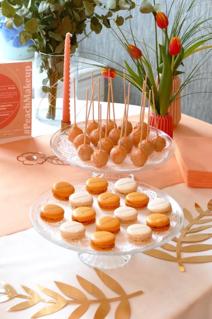 Evénement pêche Estée Lauder par Studio Candy avec table sur mesure décorée avec cakepops et cupcakes pêches, sablés décorés personnalisés, planches cocktail estivales et fontaines à boissons