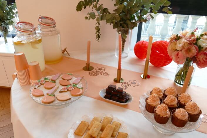 Evénement pêche Estée Lauder par Studio Candy avec table sur mesure décorée avec cakepops et cupcakes pêches, sablés décorés personnalisés, planches cocktail estivales et fontaines à boissons