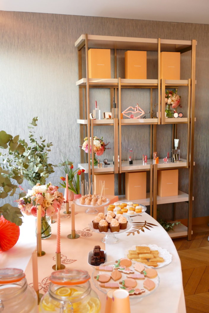 Evénement pêche Estée Lauder par Studio Candy avec table sur mesure décorée avec cakepops et cupcakes pêches, sablés décorés personnalisés, planches cocktail estivales et fontaines à boissons