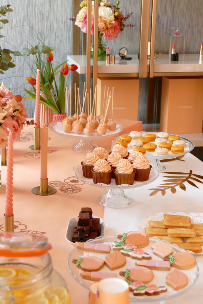 Evénement pêche Estée Lauder par Studio Candy avec table sur mesure décorée avec cakepops et cupcakes pêches, sablés décorés personnalisés, planches cocktail estivales et fontaines à boissons