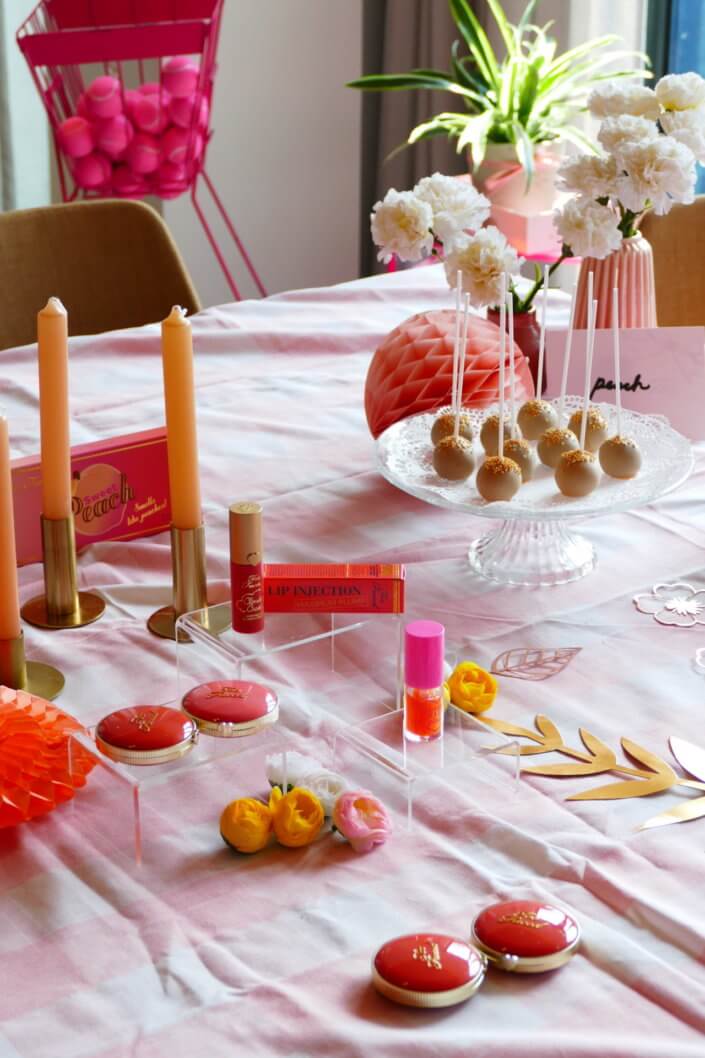lancement événement Too Faced avec set up par Studio Candy avec pâtisseries sur mesure, sablés décorés mascara, madeleines roses pailletées, cakepops chocolats, panier de pêches, décoration et scénographie