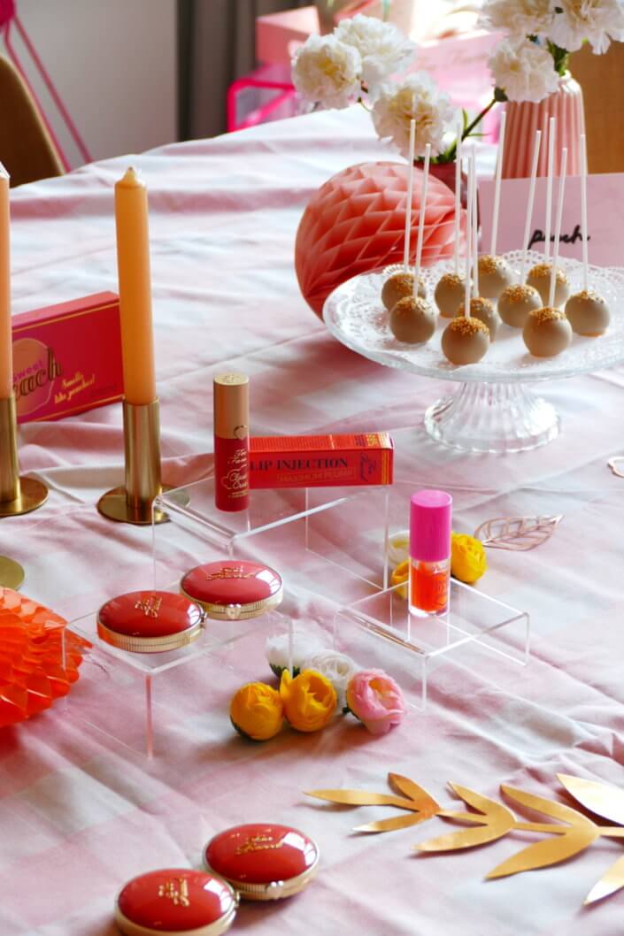 lancement événement Too Faced avec set up par Studio Candy avec pâtisseries sur mesure, sablés décorés mascara, madeleines roses pailletées, cakepops chocolats, panier de pêches, décoration et scénographie