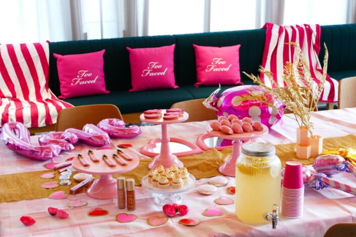 lancement événement Too Faced avec set up par Studio Candy avec pâtisseries sur mesure, sablés décorés mascara, madeleines roses pailletées, cakepops chocolats, panier de pêches, décoration et scénographie