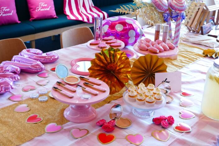 lancement événement Too Faced avec set up par Studio Candy avec pâtisseries sur mesure, sablés décorés mascara, madeleines roses pailletées, cakepops chocolats, panier de pêches, décoration et scénographie