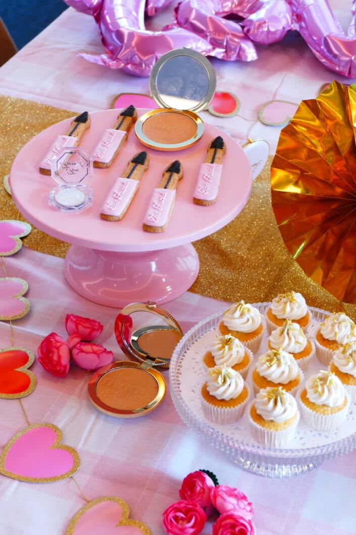 lancement événement Too Faced avec set up par Studio Candy avec pâtisseries sur mesure, sablés décorés mascara, madeleines roses pailletées, cakepops chocolats, panier de pêches, décoration et scénographie