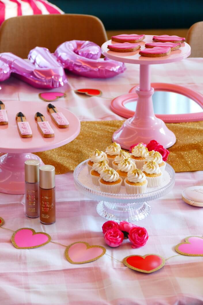 lancement événement Too Faced avec set up par Studio Candy avec pâtisseries sur mesure, sablés décorés mascara, madeleines roses pailletées, cakepops chocolats, panier de pêches, décoration et scénographie