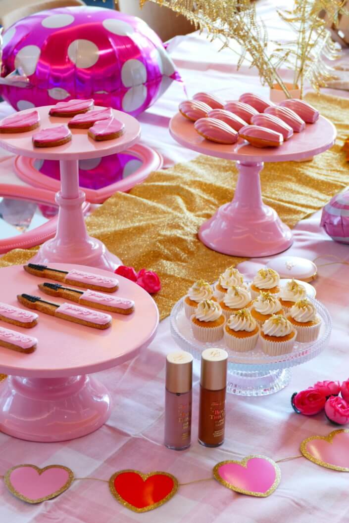 lancement événement Too Faced avec set up par Studio Candy avec pâtisseries sur mesure, sablés décorés mascara, madeleines roses pailletées, cakepops chocolats, panier de pêches, décoration et scénographie