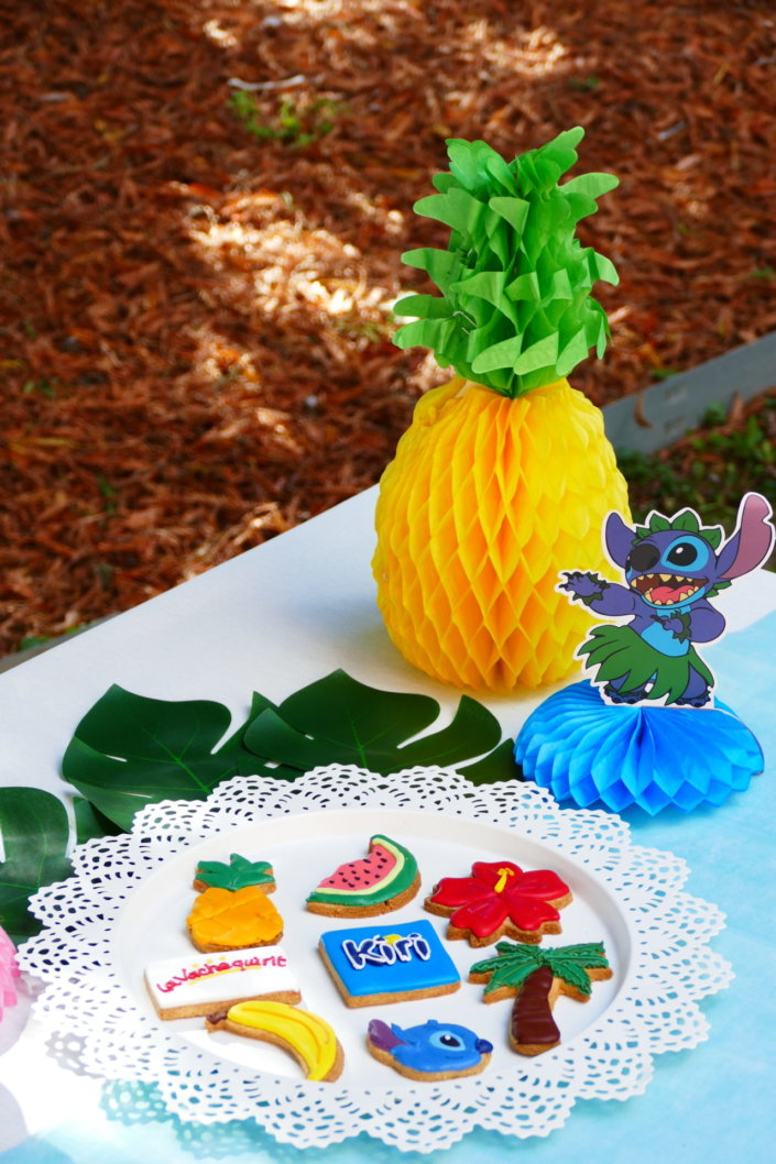 Goûter pour Kiri sur le thème de la nouvelle licence Lilo et Stitch qui sera présente sur les packagings. Table dressée sur mesure avec des cupcakes bleus, des sablés décorés Lilo et Stitch, décoration tropicale
