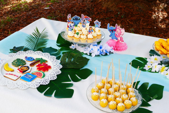 Goûter pour Kiri sur le thème de la nouvelle licence Lilo et Stitch qui sera présente sur les packagings. Table dressée sur mesure avec des cupcakes bleus, des sablés décorés Lilo et Stitch, décoration tropicale