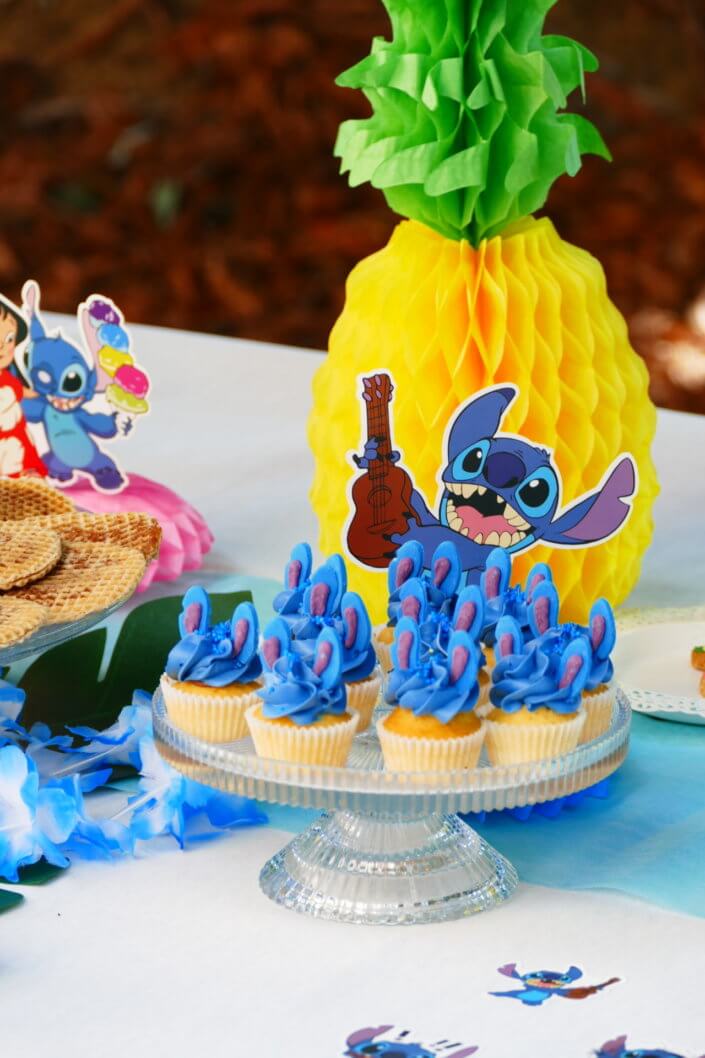 Goûter pour Kiri sur le thème de la nouvelle licence Lilo et Stitch qui sera présente sur les packagings. Table dressée sur mesure avec des cupcakes bleus, des sablés décorés Lilo et Stitch, décoration tropicale