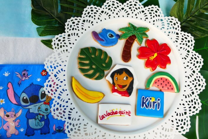 Goûter pour Kiri sur le thème de la nouvelle licence Lilo et Stitch qui sera présente sur les packagings. Table dressée sur mesure avec des cupcakes bleus, des sablés décorés Lilo et Stitch, décoration tropicale
