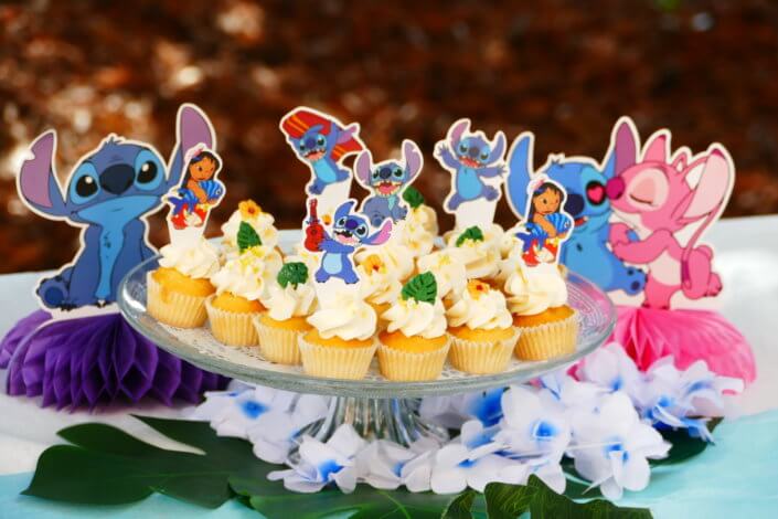 Goûter pour Kiri sur le thème de la nouvelle licence Lilo et Stitch qui sera présente sur les packagings. Table dressée sur mesure avec des cupcakes bleus, des sablés décorés Lilo et Stitch, décoration tropicale