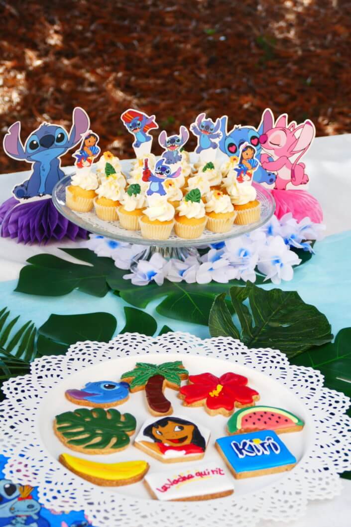 Goûter pour Kiri sur le thème de la nouvelle licence Lilo et Stitch qui sera présente sur les packagings. Table dressée sur mesure avec des cupcakes bleus, des sablés décorés Lilo et Stitch, décoration tropicale