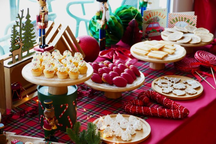 Arbre de Noël chez Inicéa par Studio Candy avec un grand goûter de Noël traditionnel, sablés décorés, cakepops rouges, cupcakes, madeleines à coques rouges, et décoration en rouge, tartan écossais et sucres d'orge
