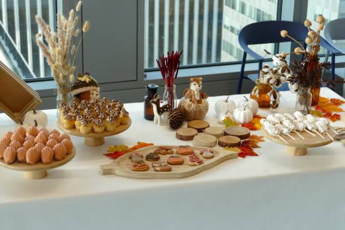 Goûter d'automne pour Axa par Studio Candy avec une scénographie et décoration automnale, des sablés décorés aux épices, des madeleines à coques orangées, des cupcakes pralinés