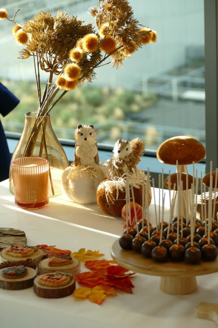 Goûter d'automne pour Axa par Studio Candy avec une scénographie et décoration automnale, des sablés décorés aux épices, des madeleines à coques orangées, des cupcakes pralinés
