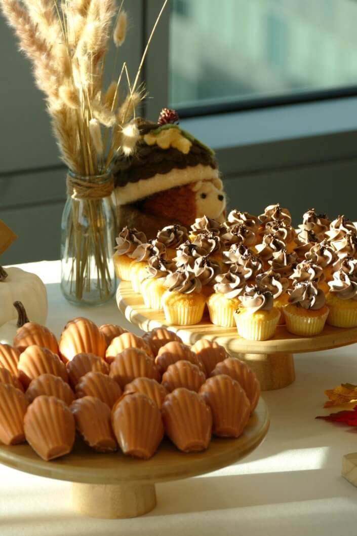 Goûter d'automne pour Axa par Studio Candy avec une scénographie et décoration automnale, des sablés décorés aux épices, des madeleines à coques orangées, des cupcakes pralinés