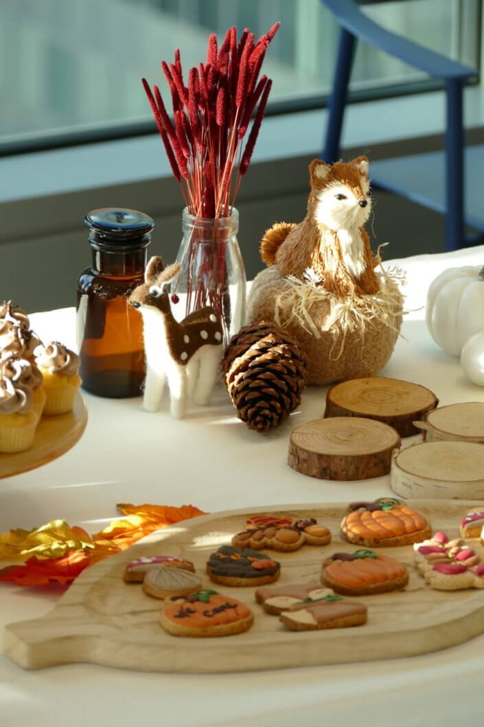 Goûter d'automne pour Axa par Studio Candy avec une scénographie et décoration automnale, des sablés décorés aux épices, des madeleines à coques orangées, des cupcakes pralinés