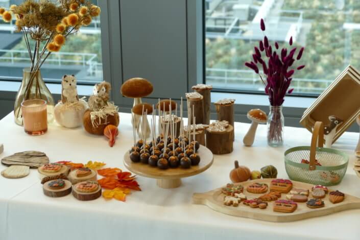 Goûter d'automne pour Axa par Studio Candy avec une scénographie et décoration automnale, des sablés décorés aux épices, des madeleines à coques orangées, des cupcakes pralinés