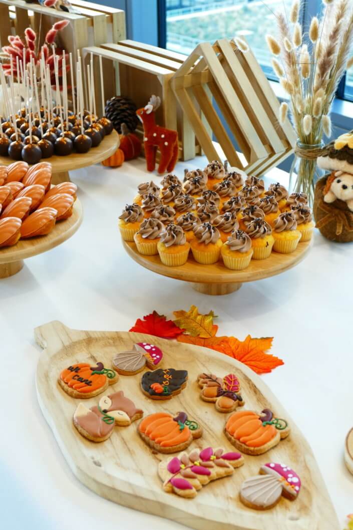 Goûter d'automne pour Axa par Studio Candy avec une scénographie et décoration automnale, des sablés décorés aux épices, des madeleines à coques orangées, des cupcakes pralinés