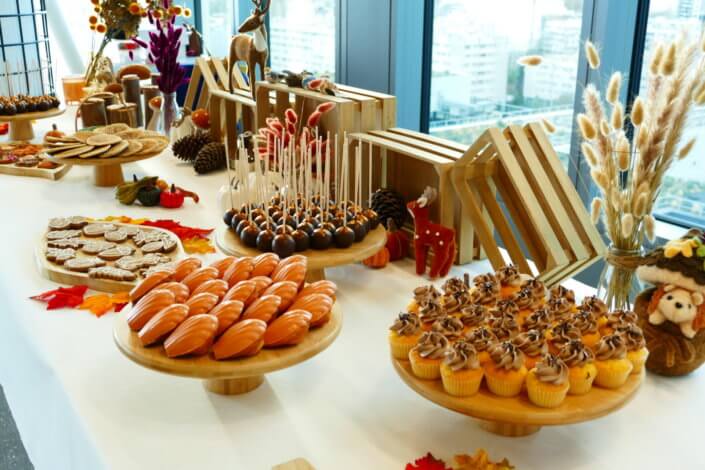 Goûter d'automne pour Axa par Studio Candy avec une scénographie et décoration automnale, des sablés décorés aux épices, des madeleines à coques orangées, des cupcakes pralinés