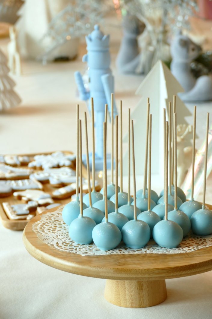 Arbre de Noël thème polaire en blanc, bleu glacier et argent : madeleines à coques bleues, sablés décorés de Noël, cakepops blancs à paillettes, cupcakes et décoration ours polaire, pingouin et casses noisettes bleu pastel peints à la main