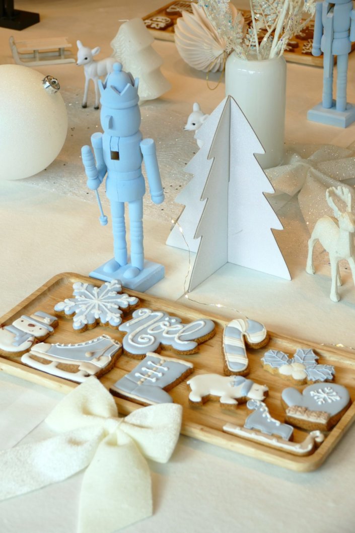 Arbre de Noël thème polaire en blanc, bleu glacier et argent : madeleines à coques bleues, sablés décorés de Noël, cakepops blancs à paillettes, cupcakes et décoration ours polaire, pingouin et casses noisettes bleu pastel peints à la main