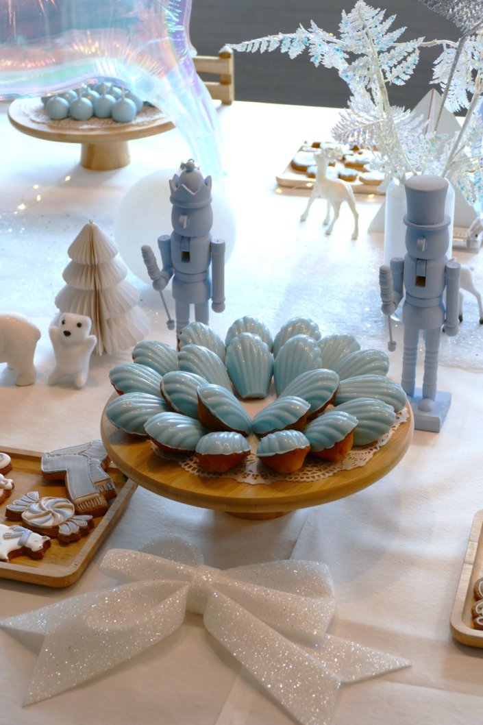 Arbre de Noël thème polaire en blanc, bleu glacier et argent : madeleines à coques bleues, sablés décorés de Noël, cakepops blancs à paillettes, cupcakes et décoration ours polaire, pingouin et casses noisettes bleu pastel peints à la main
