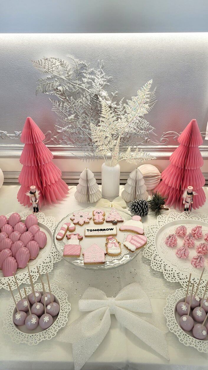 Goûter de Noël en rose et blanc pour l'agence Grenadine Rp par Studio Candy avec des pâtisseries sur mesure, un set up et une décoration rose pastel, blanc et argent