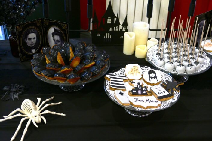 Goûter lancement film la famille addams par Studio Candy avec une scénographie sur mesure et des pâtisseries en noir et blanc, sablés décorés manoir, la chose, nattes de Mercredi et cercueil