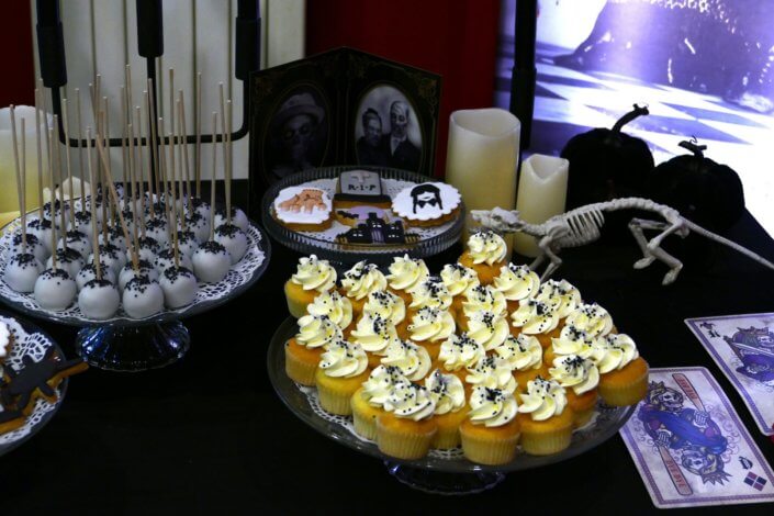 Goûter lancement film la famille addams par Studio Candy avec une scénographie sur mesure et des pâtisseries en noir et blanc, sablés décorés manoir, la chose, nattes de Mercredi et cercueil