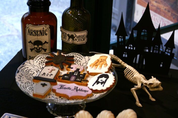 Goûter lancement film la famille addams par Studio Candy avec une scénographie sur mesure et des pâtisseries en noir et blanc, sablés décorés manoir, la chose, nattes de Mercredi et cercueil