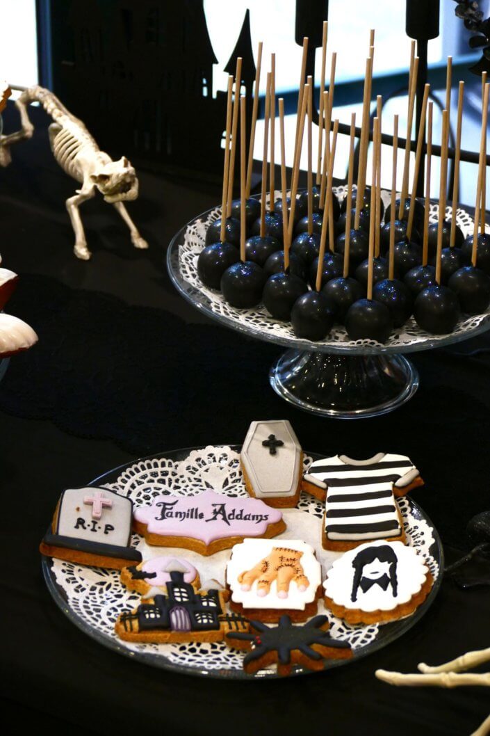 Goûter lancement film la famille addams par Studio Candy avec une scénographie sur mesure et des pâtisseries en noir et blanc, sablés décorés manoir, la chose, nattes de Mercredi et cercueil