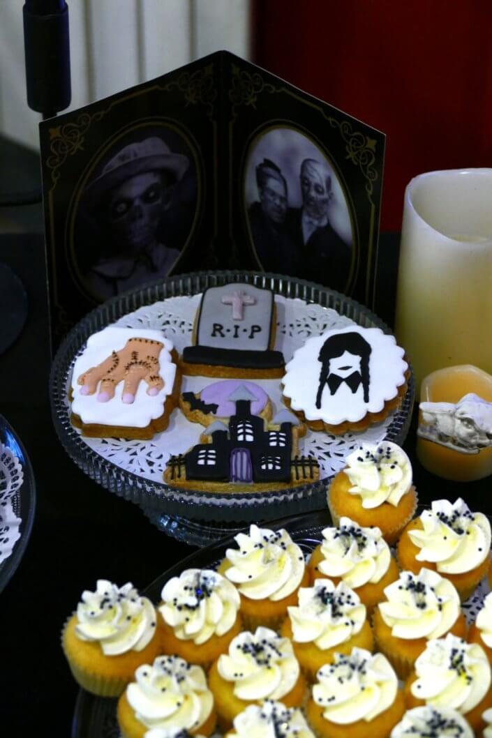 Goûter lancement film la famille addams par Studio Candy avec une scénographie sur mesure et des pâtisseries en noir et blanc, sablés décorés manoir, la chose, nattes de Mercredi et cercueil