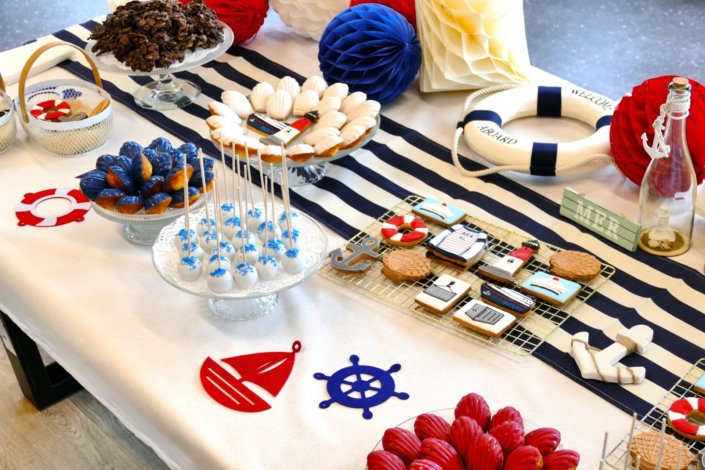 Goûter thème marine pour Axa XL réalisé par studio candy avec une décoration sur mesure, des pâtisseries personnalisées comme des cakepops bleu marine, des sablés ancre, bouée, bateau, coquillage, et une décoration en bleu, blanc et rouge
