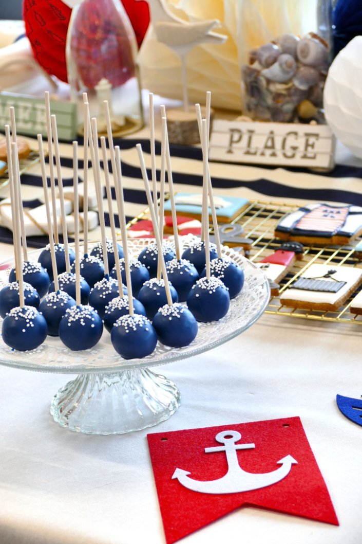 Goûter thème marine pour Axa XL réalisé par studio candy avec une décoration sur mesure, des pâtisseries personnalisées comme des cakepops bleu marine, des sablés ancre, bouée, bateau, coquillage, et une décoration en bleu, blanc et rouge