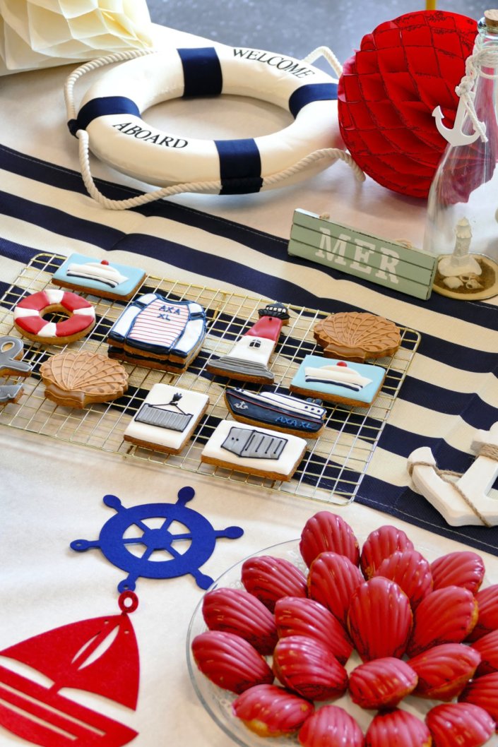 Goûter thème marine pour Axa XL réalisé par studio candy avec une décoration sur mesure, des pâtisseries personnalisées comme des cakepops bleu marine, des sablés ancre, bouée, bateau, coquillage, et une décoration en bleu, blanc et rouge