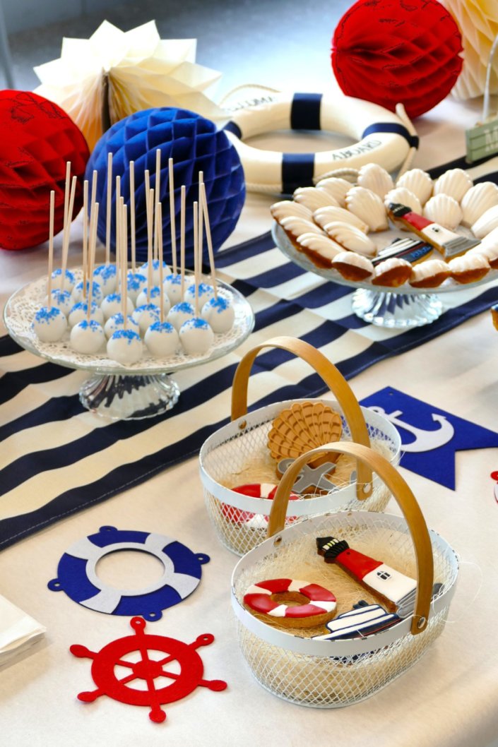 Goûter thème marine pour Axa XL réalisé par studio candy avec une décoration sur mesure, des pâtisseries personnalisées comme des cakepops bleu marine, des sablés ancre, bouée, bateau, coquillage, et une décoration en bleu, blanc et rouge