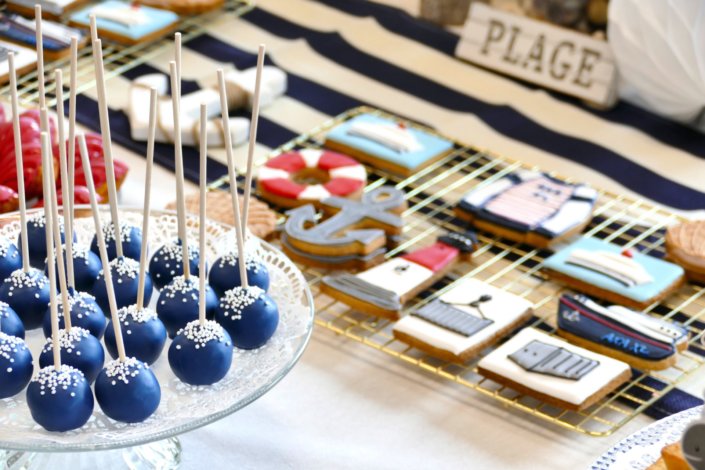 Goûter thème marine pour Axa XL réalisé par studio candy avec une décoration sur mesure, des pâtisseries personnalisées comme des cakepops bleu marine, des sablés ancre, bouée, bateau, coquillage, et une décoration en bleu, blanc et rouge