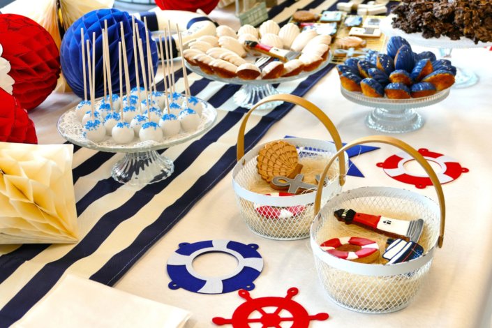 Goûter thème marine pour Axa XL réalisé par studio candy avec une décoration sur mesure, des pâtisseries personnalisées comme des cakepops bleu marine, des sablés ancre, bouée, bateau, coquillage, et une décoration en bleu, blanc et rouge